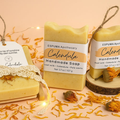 Calendula handmade soap by Espuma Apothecary made with goat milk and calendula, displayed with dried calendula petals and natural textures on a soft peach background.