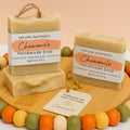 Chamomile handmade soap by Espuma Apothecary displayed in light cream bars with chamomile flowers on a wooden surface.