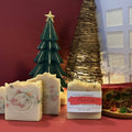 Fruit Cake handmade soap by Espuma Apothecary displayed in light-colored bars with colorful fruit-like pieces, shown in a festive holiday setting.