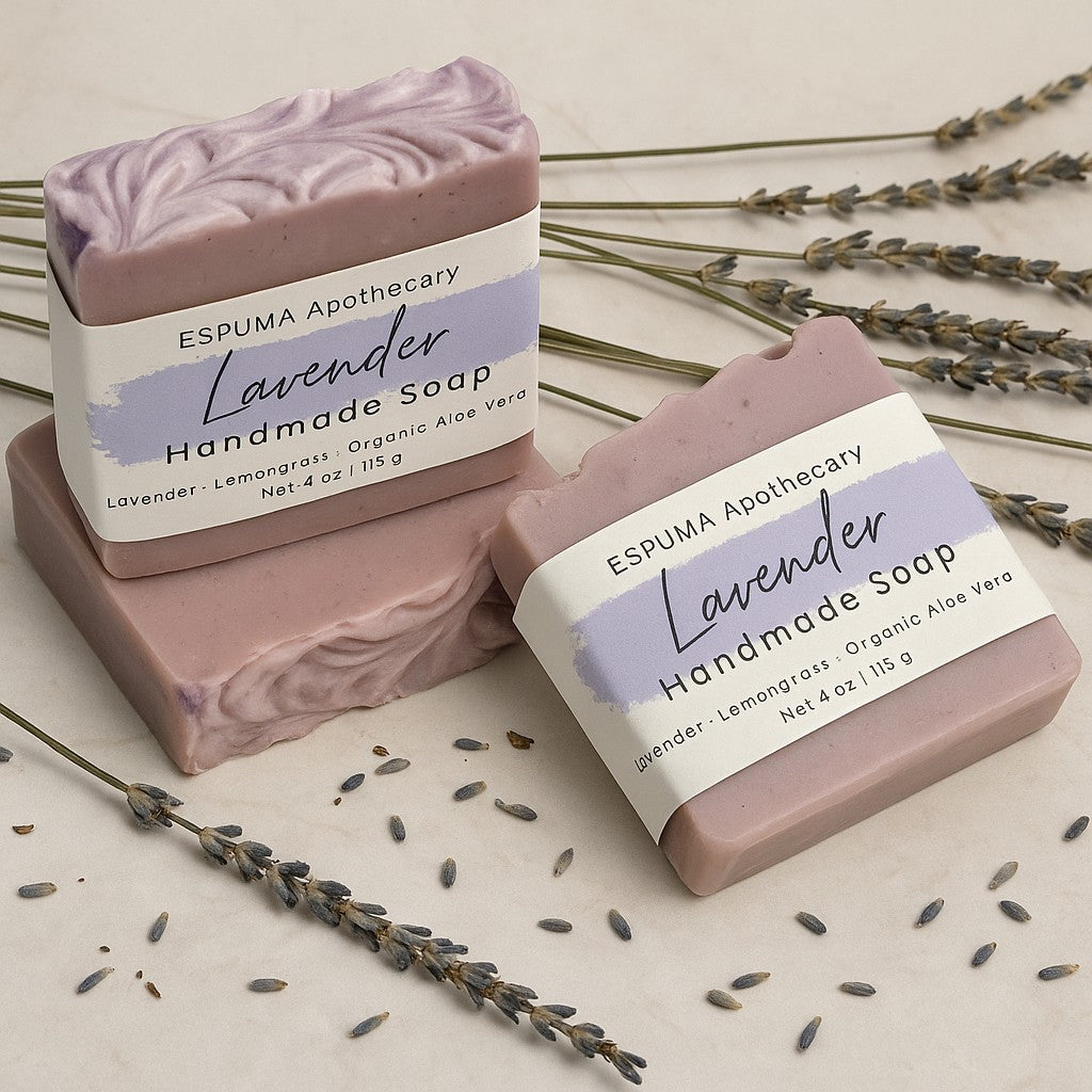 Two bars of Lavender handmade soap by Espuma Apothecary displayed with dried lavender flowers and seeds on a light surface.