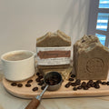 Morning Café handmade soap by Espuma Apothecary displayed in brown speckled bars with coffee beans and a coffee cup on a wooden surface.