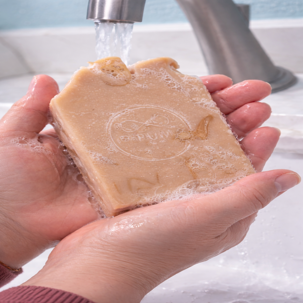 Bar of soap being held under running water with a blurred background